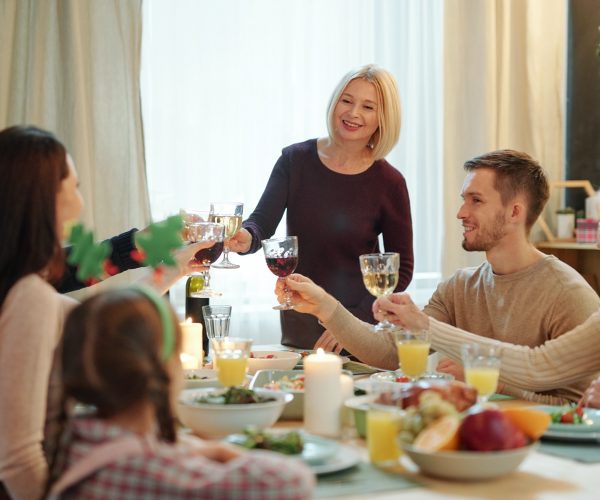 Blonde mature female and her family members clinking with glasses of wine