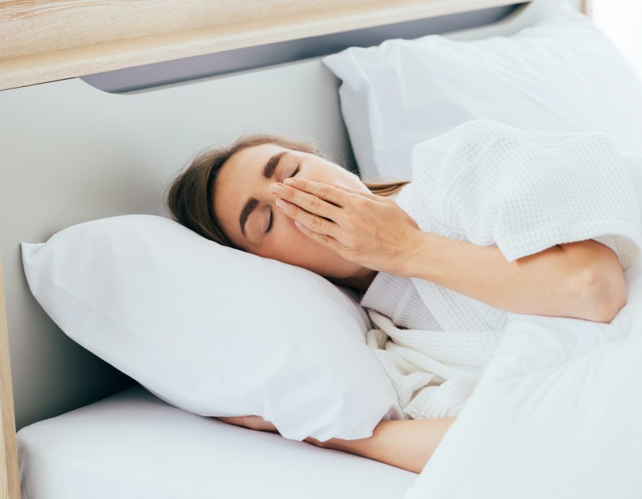 Sleepy woman yawning in bed